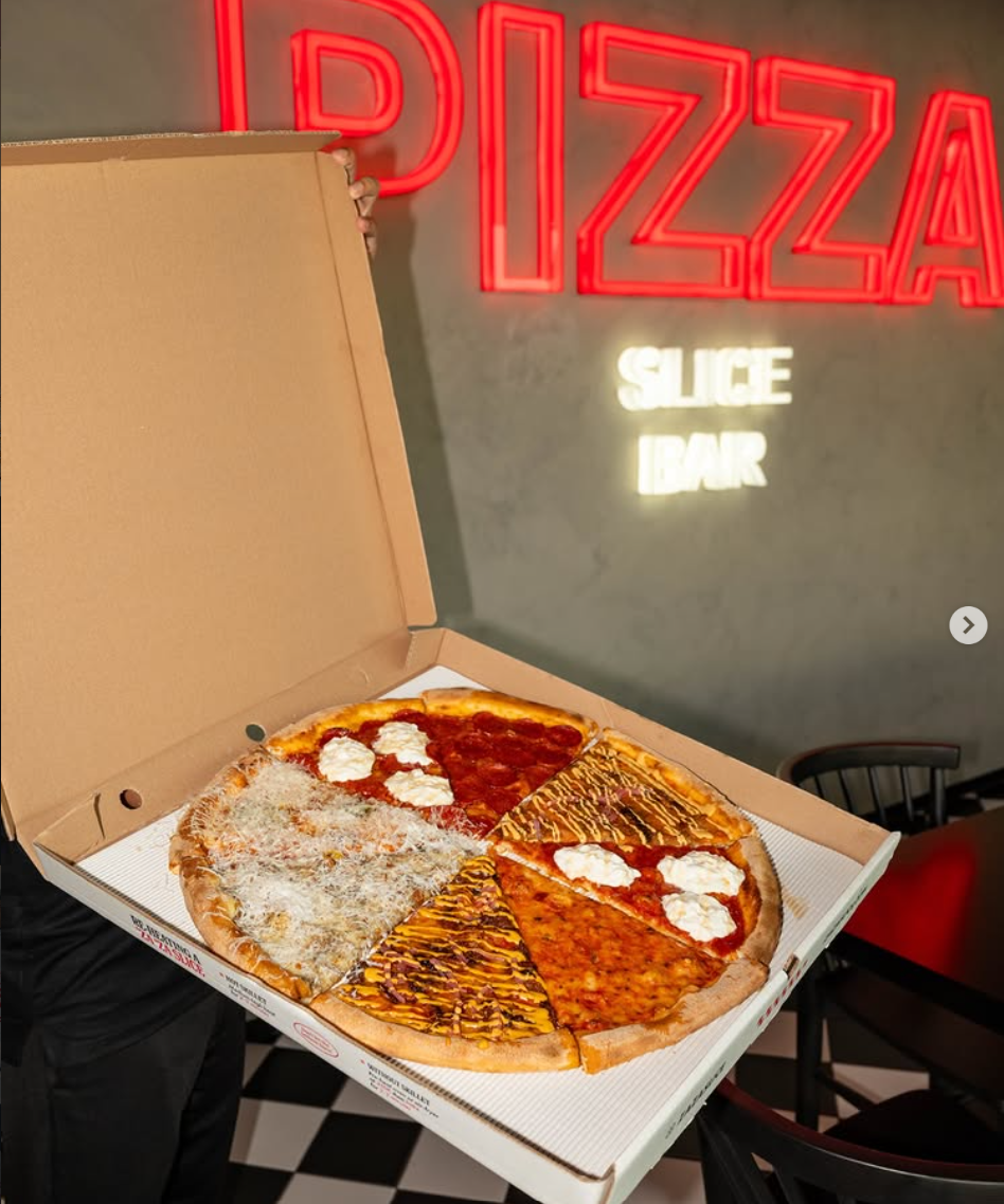 Open pizza box under the neon Pizza Slice Bar sign