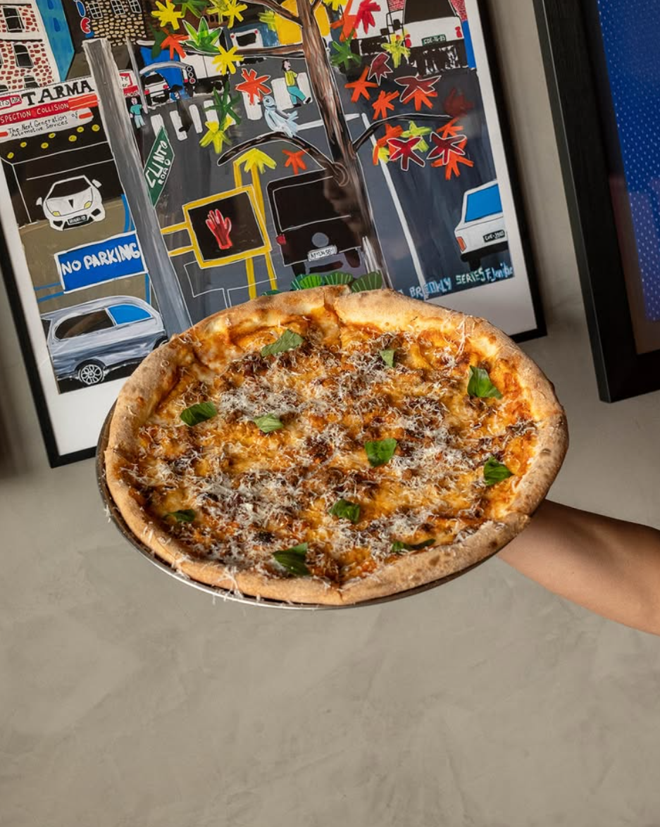House Margherita 20-inch pie held up against a gallery wall